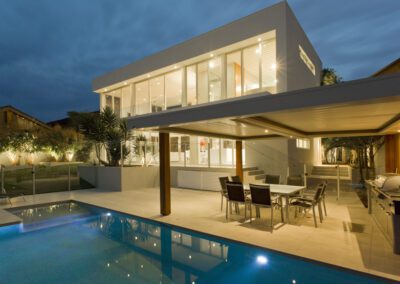 Modern house at dusk with swimming pool and barbecue in backyard