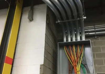 Conduit pipes and organized electrical wiring in a commercial building's utility area.